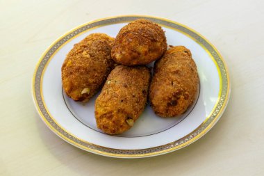 Beyaz bir tabakta hafif bir ahşap zemine karşı nefis ev yapımı, loş pirzola. Yumurta pirzolası, Bangladeş mutfağında popüler ve lezzetli bir aperatiftir..