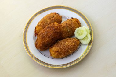 Beyaz bir tabakta hafif ahşap arka planda nefis ev yapımı, loş pirzola. Bu popüler ve sevilen Bangladeş aperatifi, aynı zamanda dimer pirzola veya dimer alur pirzolası olarak da bilinir, gerçek bir ziyafet..