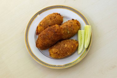 Beyaz bir tabakta hafif ahşap arka planda nefis ev yapımı, loş pirzola. Bu popüler Bangladeş aperatifi, aynı zamanda dimer pirzola veya dimer alur pirzolası olarak da bilinir, gerçek bir lezzettir. Üst görünüm.