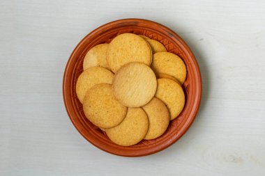 Kil tabakta hafif ahşap bir yüzeye karşı dizilmiş çıtır çıtır ve baharatlı bisküviler. Bu bisküviler hem cips hem de geleneksel bisküvileri hatırlatan eşsiz bir lezzet sunuyor. Üst görünüm.