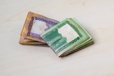 Katlanmış BDT 1000 Tk ve 500 Tk Bangladeş para birimi banknotları (toplam bin beş yüz taka) hafif ahşap bir yüzey üzerinde.
