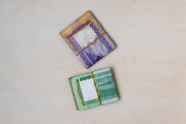 Beş yüz bin Taka Bangladeş banknotundan oluşan küçük bir deste, tahta bir arka planda lastik bantla bağlanmış. BDT parası (1000 ve 500 Tk). Üst görünüm.