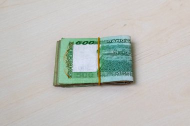 Beş yüz Bangladeş 'li küçük deste banknotlar hafif ahşap bir yüzeye lastik bantla bağlanmış. BDT 500 Tk 'ye yakın çekim.