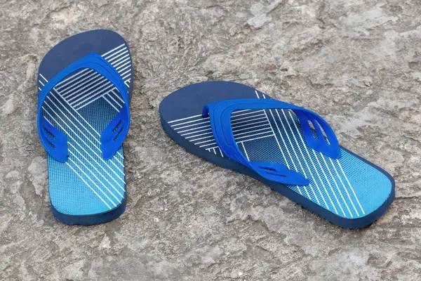 Beton zeminde bir çift şık lacivert parmak arası terlik. Bu hafif, sandalet benzeri ayakkabılar genellikle sıradan ayakkabılar olarak giyilir..