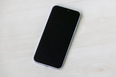 Açık ahşap yüzeyde ekranı kapalı akıllı telefon. Siyah ekranlı Android cep telefonu.