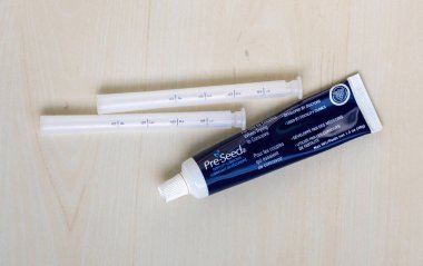 Tahta bir yüzey üzerinde aplikatörleri olan erken tohumlu kayganlaştırıcı tüp. Hamile kalmaya çalışan çiftler için en iyisi ve geliştirilmiş cinsel deneyim için yağlayıcı bir jel..