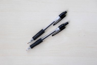 Hafif ahşap bir yüzeyde iki tükenmez kalem. Çalışmak ve çalışmak için çok önemli bir araç. Üst görünüm.