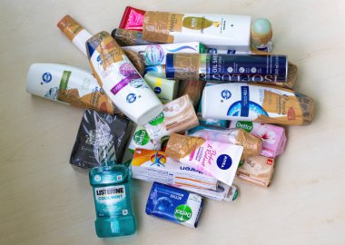 Şampuan, yüz yıkama, krem, losyon, parfüm, vücut spreyi, diş macunu, sabun ve gargara gibi çeşitli güzellik ve kozmetik ürünleri ahşap bir arka planda sergilenmektedir. Hediye örneği.