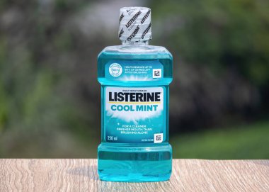 Listerine Cool Mint 250 ml Ağız gargarası şişesi ahşap üzerine yeşil arka plan, günlük ağız temizliği ürünü.