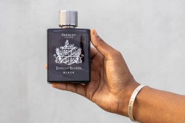 Yardley London İngiliz Blazer Black Eau de Parfum şişesini beyaz arka planda tutan kadın eli..
