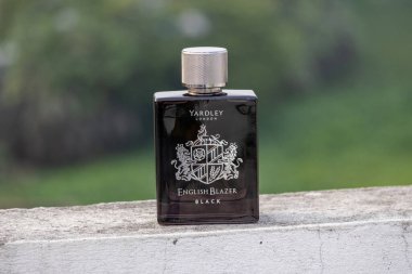 Yardley London İngiliz Blazer Black EDP şişesi yıpranmış beyaz dış duvar, bulanık doğal manzara. Ön çekim..