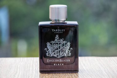 Yardley London İngiliz Blazer Black Eau de Parfum şişesi ahşap üzerinde, bulanık bir tabiatı var. Cam şişenin önü..