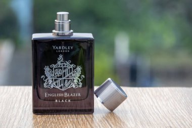 Yardley London İngiliz Blazer Black Eau de Parfum şişesi, kapağı açık, tahtada, bulanık doğa arka planı var. Cam şişenin önü..