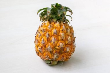 Hafif ahşap zemin üzerinde taze olgun ananas (Ananas comosus). Sağlıklı meyve, vitamin, mineral, lif ve antioksidan açısından zengin..