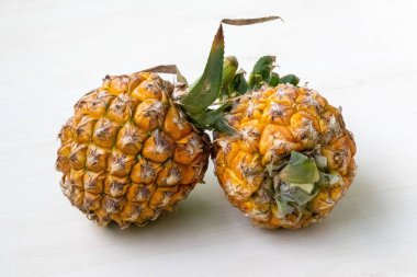 İki olgun ananas (Ananas comosus) hafif ahşap üzerinde. Vitaminli, mineralli, lifli ve antioksidanlı sağlıklı meyve..