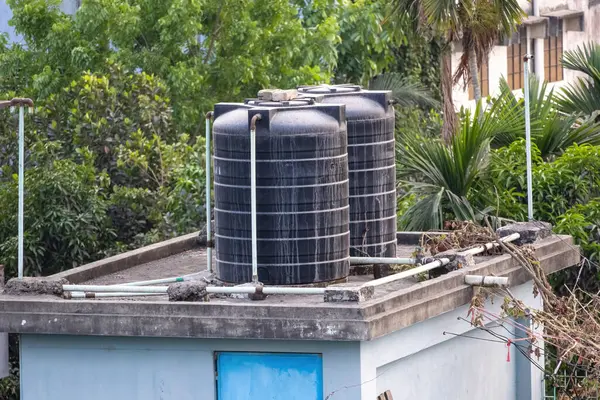 Bangladeş 'teki bir binanın çatısında iki siyah plastik su tankı..