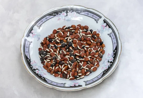 Seramik tabakta kurumuş Hyacinth fasulyesi (Labaratuvar purpureus) tohumları, beyaz arkaplan.