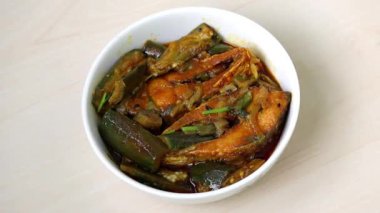 Otantik Bengali brinjal ve Hilsa balıklı köri. Lezzetli, popüler yemek beyaz kasede hafif ahşap üzerinde servis ediliyor..