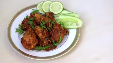 Acılı ve Baharatlı Tavuk Karahi Bhuna Körisi. Hakiki İranlı Kadai. Kişniş, limon, beyaz tabakta salatalık ve ahşap zemin ile süslenmiş lezzetli tavuk yemeği..
