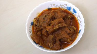 Ağız sulandıran koyun eti bhuna, baharatlı Bengali köri, ahşap masada beyaz kase içinde..