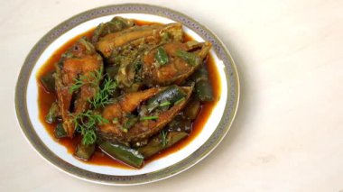 Seramik tabakta Hilsa balığı olan lezzetli brinjal (patlıcan) köri, açık ahşap yüzey. Lezzetli Bengali yemeği..