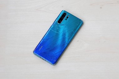 Hasarlı Huawei P30 Pro, kırık ekran ve tahta üzerindeki arka panel. Akıllı telefon tamiri gerekiyor, arka plan.