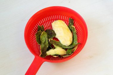 Olgun bir mango yedikten sonra, yeşil deri ve büyük tohum kırmızı plastik bir sepetin üzerinde, hafif ahşap..