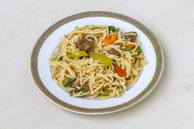 Seramik tabakta kırmızı biberli, domatesli, etli erişte. Ahşap zemin üzerinde lezzetli şehriyeler, yemek için hazır..