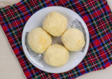 Lezzetli Bengali Kachagolla tatlılarının seramik tabakta üst görüntüsü. Yumuşak, süngerimsi dokusu ve ince tatlılığıyla ünlüdür..