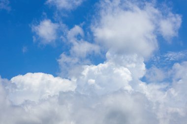 Büyük, yumuşak beyaz kümülüs bulutlarının yer aldığı göz kamaştırıcı bir gün ortası mavi gökyüzü arka planı. Herhangi bir tasarım projesi için mükemmel canlı ve açık hava.
