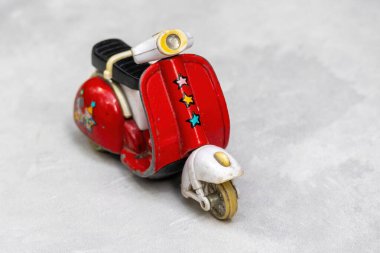 Önden görülen eski kırmızı metal oyuncak scooter, sapları ve lastikleri eksik. Bu klasik çocuk oyuncağında kırık parçalar ve yaş belirtileri var..