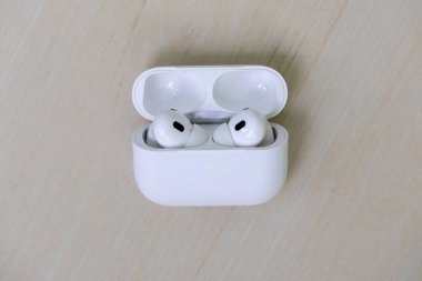 Şarj çantasındaki kablosuz kulaklıklar ahşap bir arka planda duruyor. Bu modern Bluetooth kulaklıkların üst görünümü, kullanıma hazır.