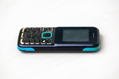 Yıllanmış, yıpranmış düğmeli, renkli kaplamalı ve ekran çizikli uzun metrajlı telefon, yoğun kullanım belirtileri gösteriyor. Teknoloji, nostalji ve klasik elektronik temalar için mükemmel..