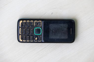 Yıllanmış uzun metrajlı telefon, rengi değişmiş vücut ve geniş kullanımlı ekranı çizilmiş. Projeleriniz için eski bir düğme aracının tepeden tırnağa görünümü.