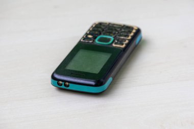 Eski, iyi kullanılmış bir cep telefonunun yakın çekimi, belirgin bir renk değişimi ve kaplamasında ve ekranında sayısız çizikler gösteriyor. Belirgin ikili LED el fenerini içerir.