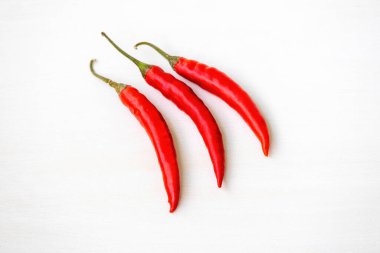 Beyaz arka planda izole edilmiş taze olgun kırmızı biberlerden oluşan canlı bir üçlü. Yemek, yemek, baharat, sağlıklı beslenme ve mutfak temaları için mükemmel..