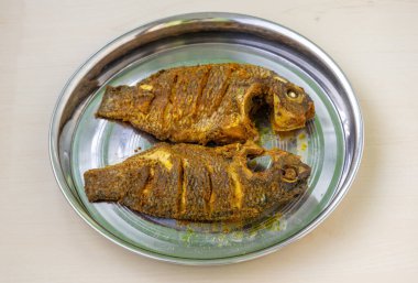 Ahşap yüzeyde, çelik tabakta tüm tilapia balığını kızartmak. Baharatlı ızgara mangal deniz ürünleri, taze pişmiş Asya mutfağı yemek fotoğrafçılığı..