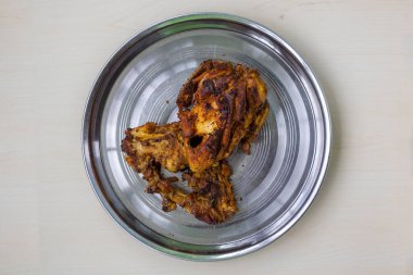 Çelik tabakta ev yapımı baharatlı kızarmış tavuk. Çıtır çıtır deri, taze et ve zengin, lezzetli bir barbekü aroması. Üst görünüm.