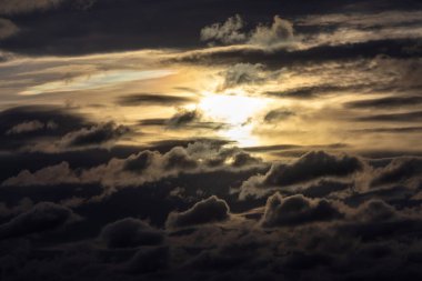 Ufkun altında yakıcı, parlayan bir güneşin battığı cesur ve canlı bir gün batımı karanlık ve dramatik bulutların üzerine sıcak bir ışık saçıyor..