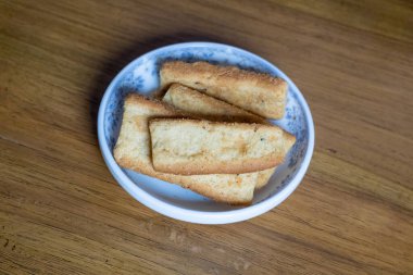 Bir fincan çay eşliğinde çıtır çıtır çay bisküvileri, bir fincan çayla eğlenmeye hazır. Ahşap arka planda tuzlu çay saati atıştırmalıkları.