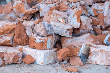 Eski, kırık kırmızı tuğla yığını. Yıkılan binadan eskimiş, desenli molozlar. Çürüyen, ufalanan kırmızı kil tuğla atığı. Mimari detaylar, inşaat enkazı, yakın çekim..
