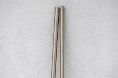 İki eski, paslanmaz çelik borunun yakın çekimi grunge beyazı boyalı bir duvara dayanıyor. Endüstriyel arka plan, doku ve kopyalama alanı.