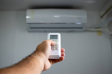 Klimayı açan kişi uzaktan kumandayı çalıştırıyor..