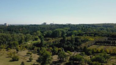 İnsansız hava aracı, bir park vahasının panoramik güzelliğini yakalıyor. İnsanlar geziniyor, inşaat halindeki yeni bir konut kompleksine bakıyor..