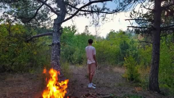 Młody Człowiek Wchłonął Się Blasku Zachodu Słońca Obok Migoczącego Ognia — Wideo stockowe