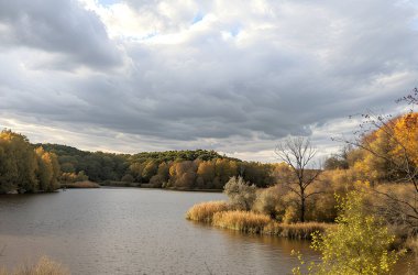 Gri bulutların heybetli kubbesinin altında, tehditkar dağlar gibi sakin bir göl yatar. Yüzeyi sonbahar manzaralarını yansıtır: sarı-kırmızı ağaçlar ve uzun kuru otlar.