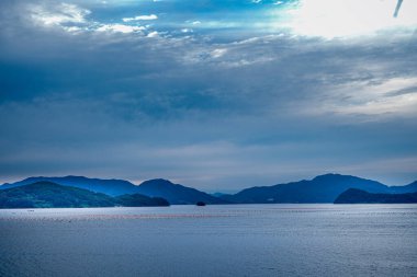 Akşam alacakaranlıkta nehir dağı ve mavi gökyüzü ile gün batımında manzara