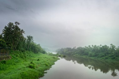 Hindistan 'da yeşil ağaçları ve dağları olan sakin bir nehrin manzarası.
