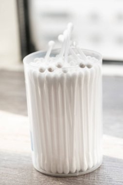 Beyaz pamuklu kulak temizleme tomurcukları beyaz arka planda konteynırda güzelce yerleştirilmiş.