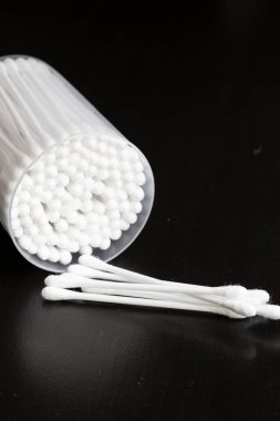 Beyaz pamuklu kulak temizleme tomurcukları siyah arka planda güzelce konteynırda yerleştirilmiş.